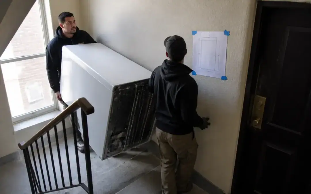 Mover carrying a wrapped item down a concrete service stairwell